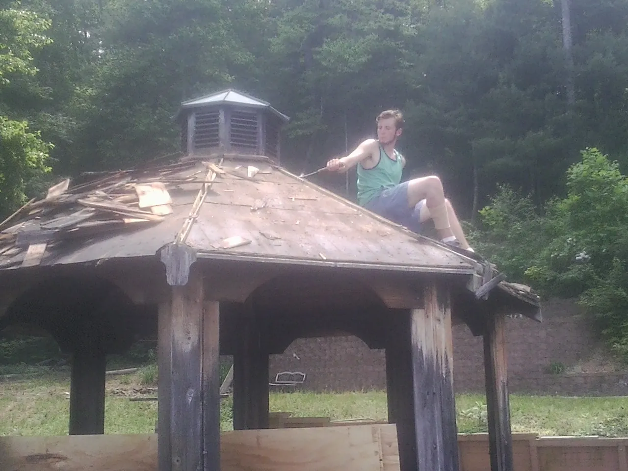 Tearing the old roof off a wooden gazebo before new shakes in Sharon